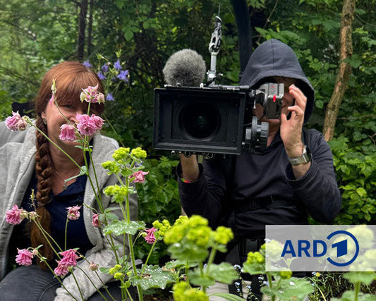 ARD Querbeet zu Besuch bei Sarah Stiller: Moderatorin Sabrina Nitsche beim Dreh im blühenden Cottage Garten mit Kamerateam.