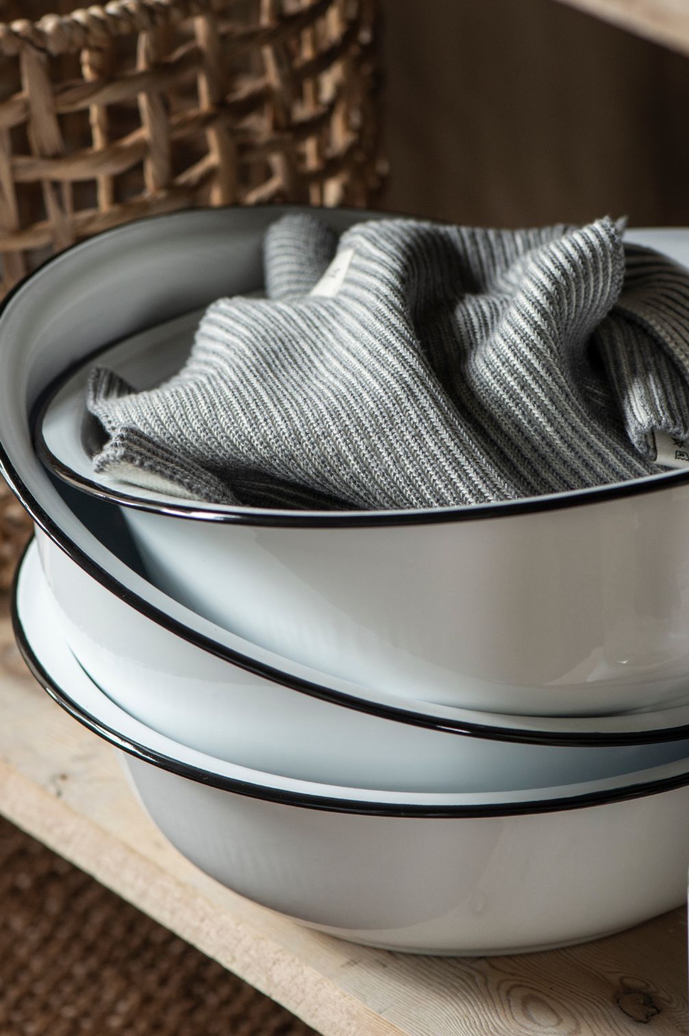 Emaille-Schüssel in Weiß mit schwarzem Rand auf Holzregal mit gefaltetem Tuch dekoriert.