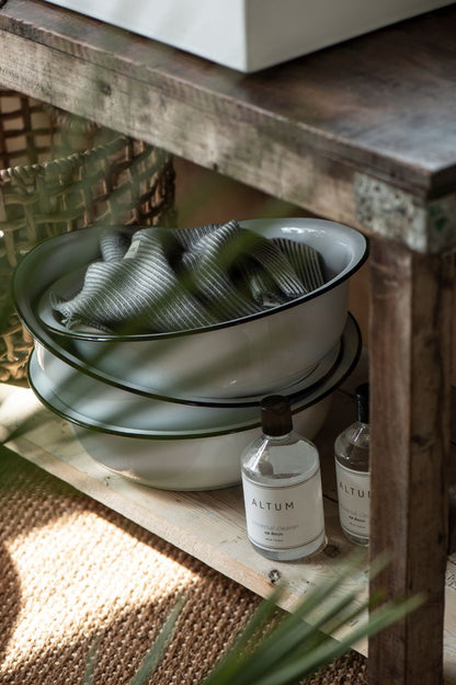 Detailansicht einer weißen Emaille-Schüssel mit schwarzem Rand auf Holzkonsole.