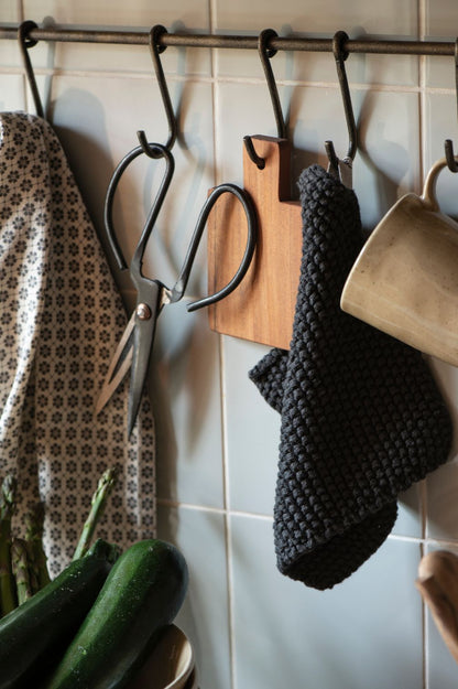 Große schwarze Metallschere an einer Hakenleiste in der Küche aufgehängt.