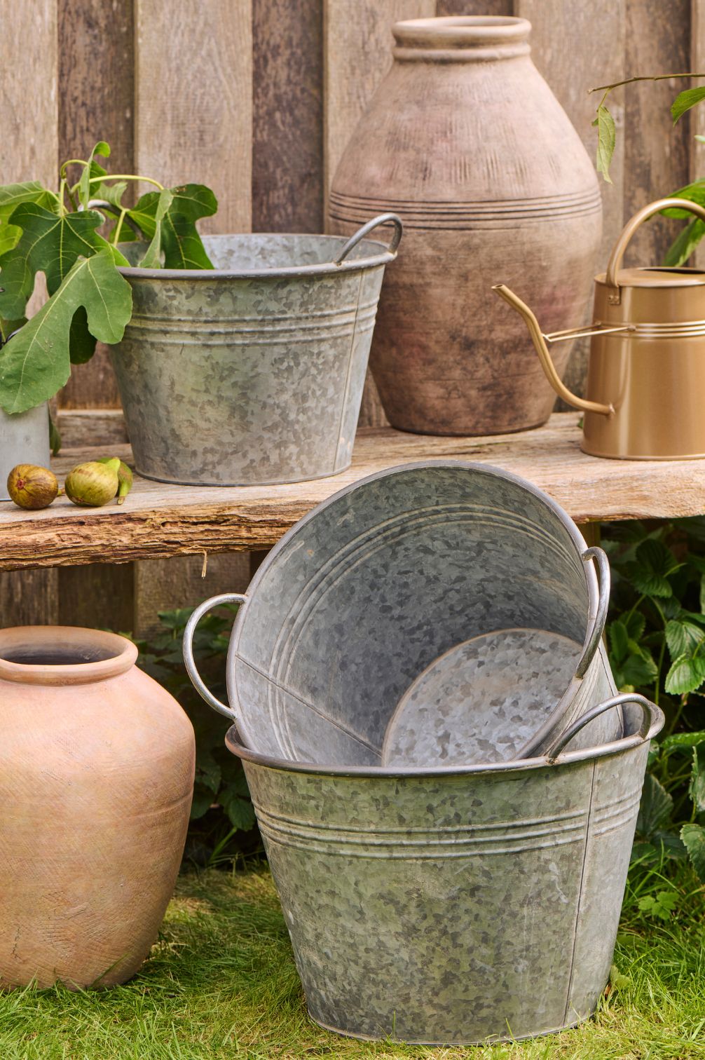 Metalltöpfe konisch im 3er-Set mit Henkeln dekorativ im Garten arrangiert.