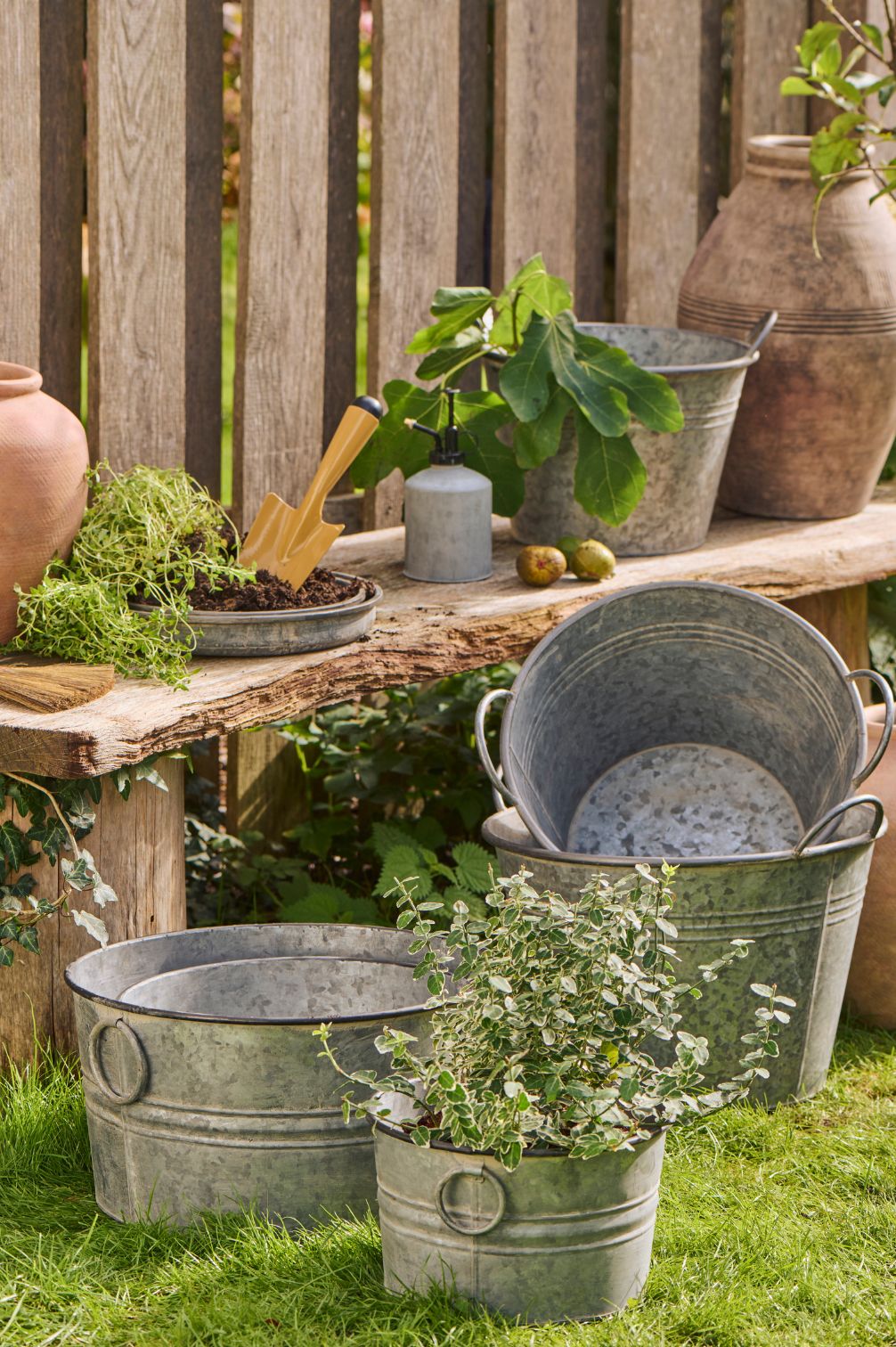 Topfsatz aus verzinktem Metall mit runden Henkeln dekorativ im Garten.