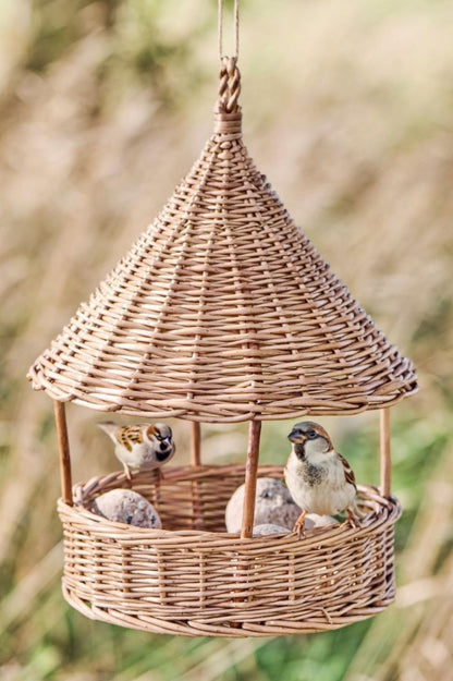 Vogelhaus aus Weide zum Aufhängen mit kleinen Vögeln im Garten.