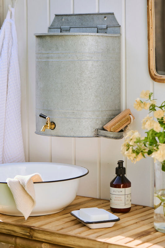 Detailaufnahme Wand-Wasserbehälter aus Metall mit Messing Wasserhahn und integrierter Seifenablage.